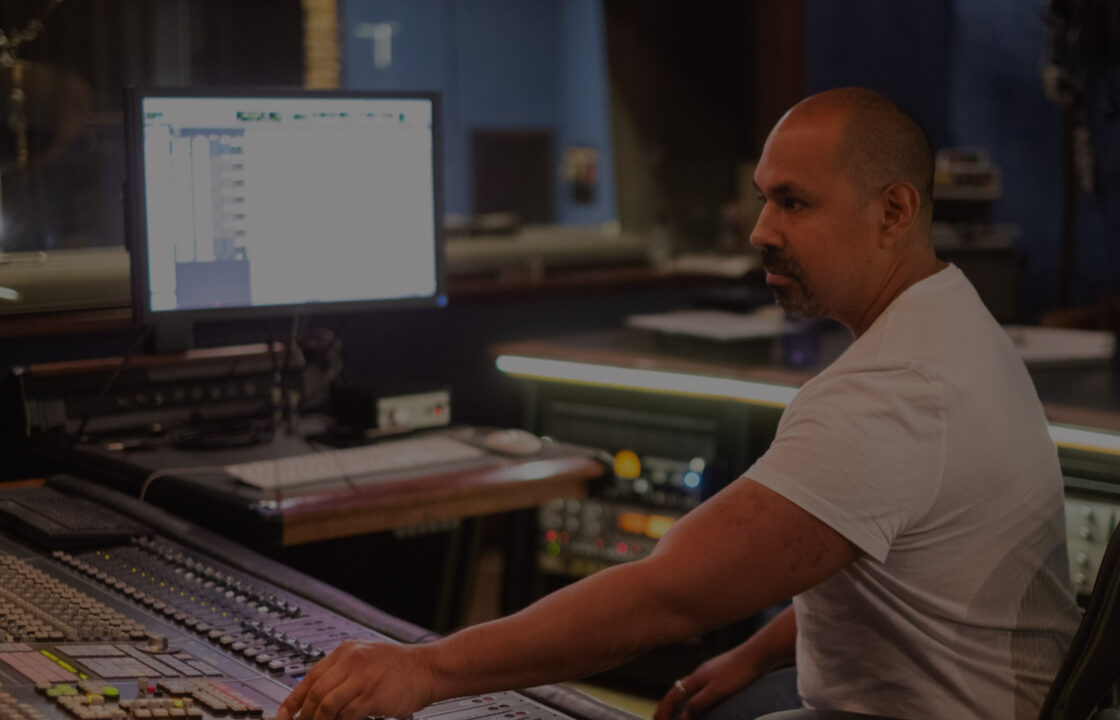 Producer behind API desk in studio hand on the faders