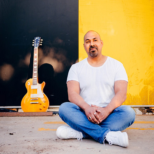 Jochem sitting on the ground with a guitar behind him